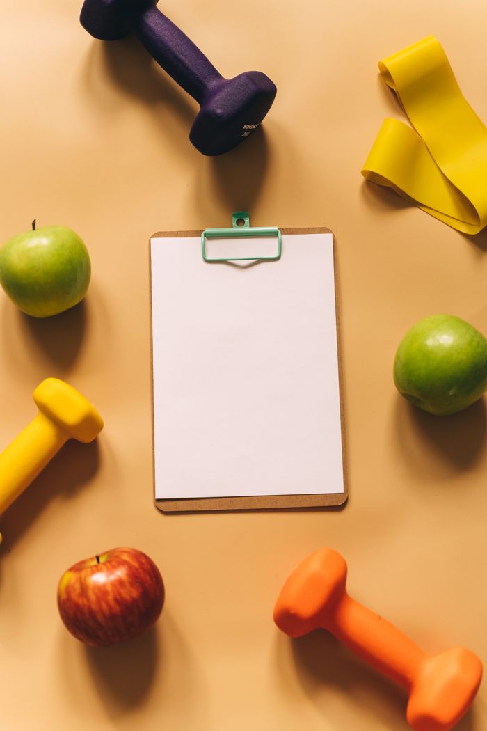 who-we-are Stylish flat lay showcasing fitness equipment and apples on a beige background for health inspiration.