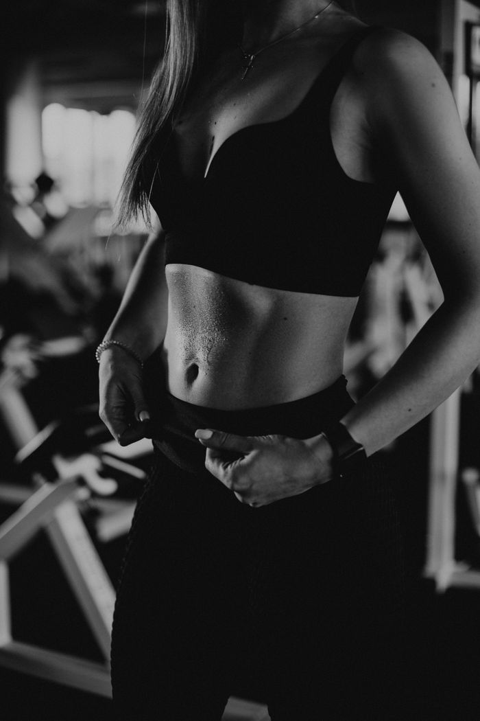 about-us Artistic black and white photo of a woman in a sports bra showing dedication to fitness.
